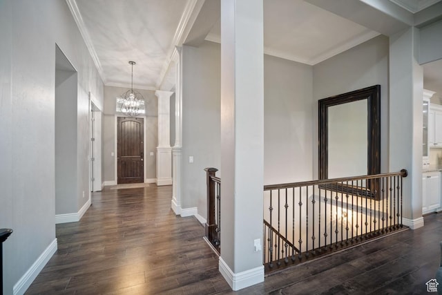 entryway featuring dark wood finished floors, a chandelier, crown molding, and baseboards