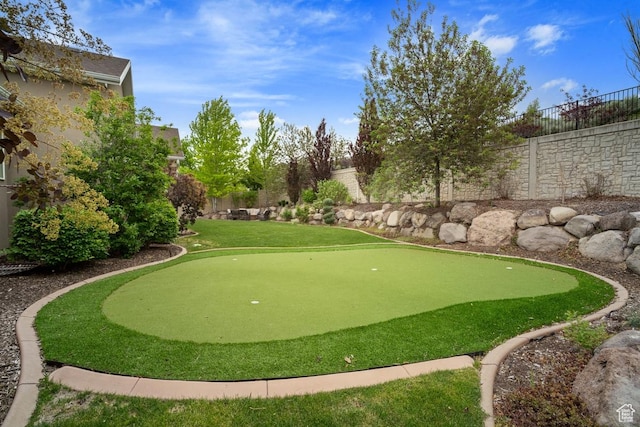view of property's community with an area to practice putting and a fenced backyard
