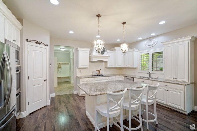 kitchen with a sink, appliances with stainless steel finishes, white cabinetry, light stone counters, and recessed lighting