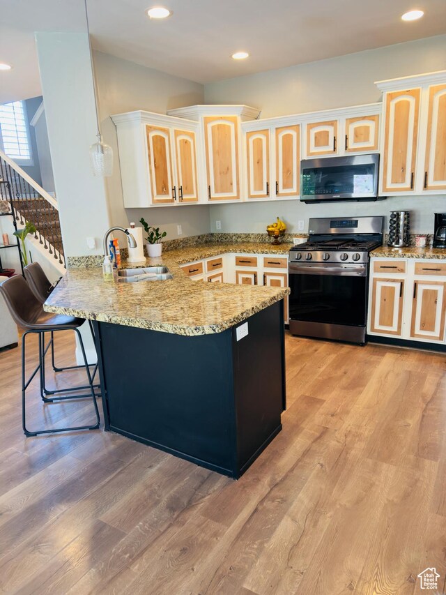 4382 N Pheasant Ridge Trl, Lehi, UT 84043 - kitchen with appliances with stainless steel finishes, a sink, a peninsula, a kitchen bar, and light brown cabinetry