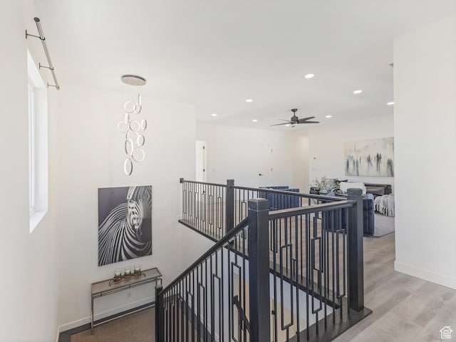 corridor featuring an upstairs landing, recessed lighting, wood finished floors, and baseboards