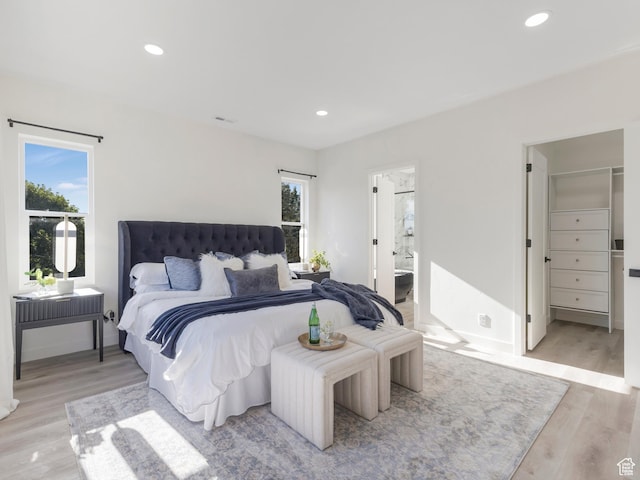 bedroom featuring light wood finished floors, recessed lighting, baseboards, and ensuite bathroom