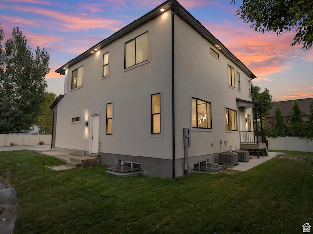 back of property at dusk featuring stucco siding, cooling unit, and a patio