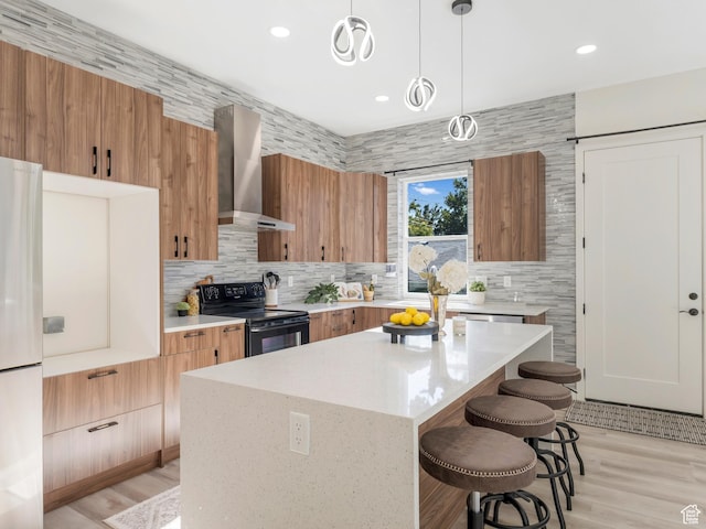 kitchen featuring electric range, wall chimney exhaust hood, freestanding refrigerator, decorative backsplash, and recessed lighting