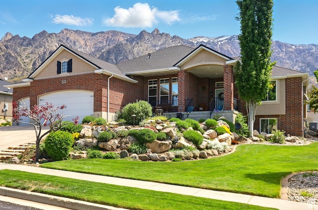7639 S 475 W, Willard, UT 84340 - view of front facade with a mountain view, a front yard, brick siding, concrete driveway, and a garage