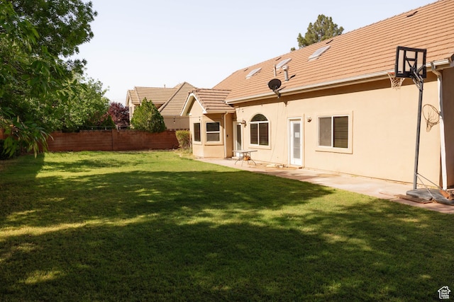 rear view of house with stucco siding, a tile roof, and a patio