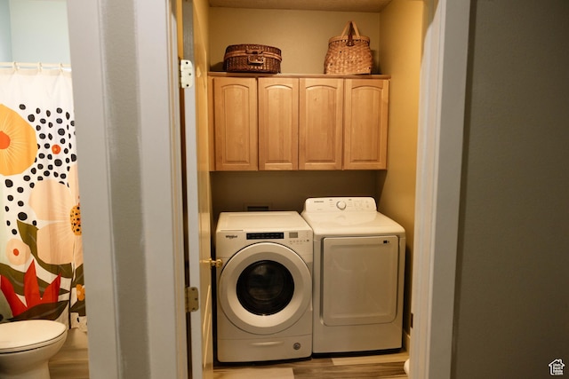 laundry area featuring independent washer and dryer, cabinet space, and wood finished floors