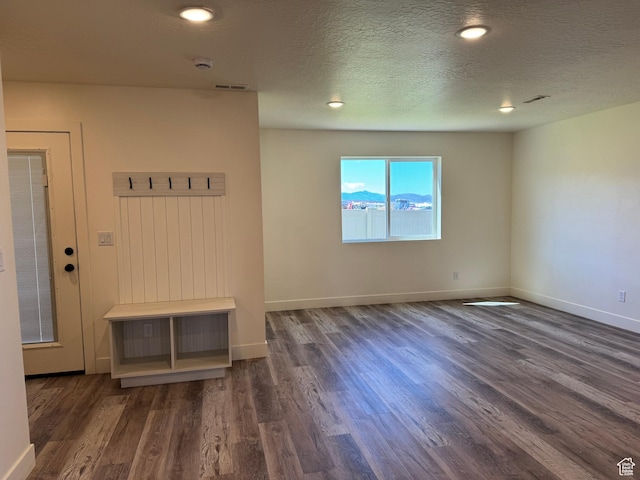 unfurnished room featuring wood finished floors, baseboards, a textured ceiling, and recessed lighting