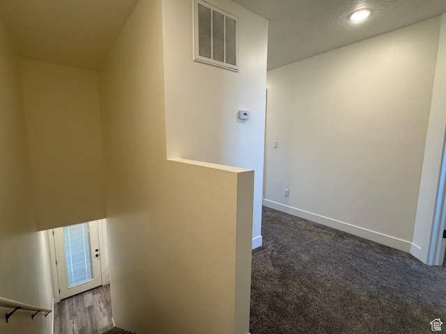 hallway with an upstairs landing, baseboards, dark colored carpet, and recessed lighting