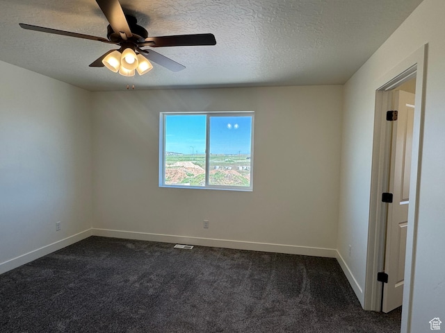 unfurnished room with a textured ceiling, dark carpet, ceiling fan, and baseboards
