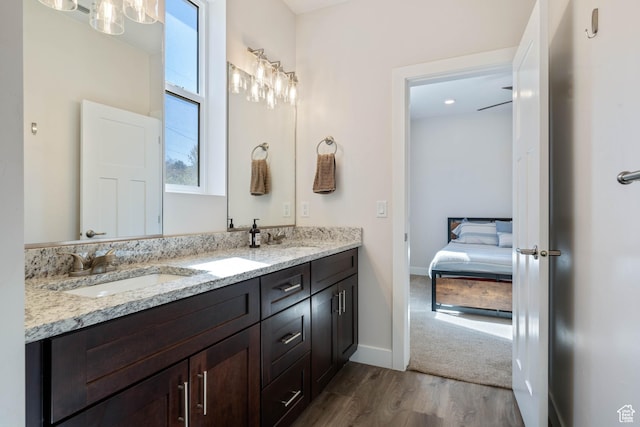 ensuite bathroom with wood finished floors, double vanity, and baseboards