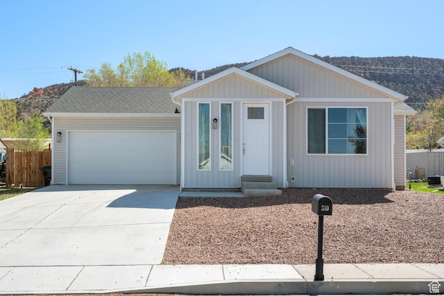 single story home with a garage, concrete driveway, and fence