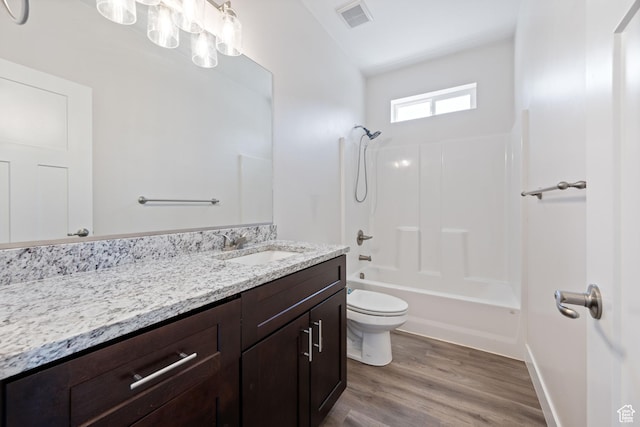 bathroom with toilet, vanity, wood finished floors, and  shower combination