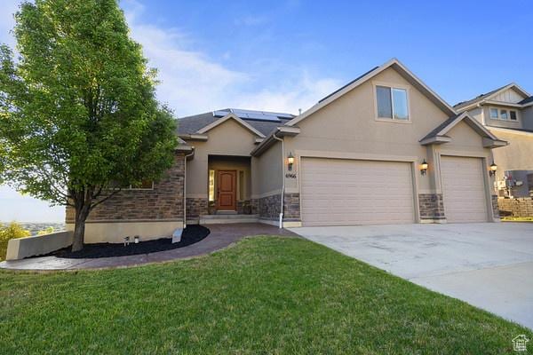 6966 N S Pass Rd, Eagle Mountain, UT 84005 - view of front of property featuring stucco siding, solar panels, driveway, a front lawn, and stone siding