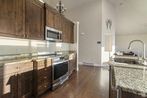 6966 N S Pass Rd, Eagle Mountain, UT 84005 - kitchen with appliances with stainless steel finishes, a sink, light stone counters, dark wood-type flooring, and lofted ceiling