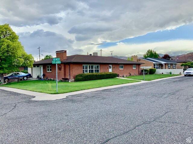 111 W 570 N, Richfield, UT 84701 - ranch-style home featuring a chimney, an attached garage, brick siding, and a front yard