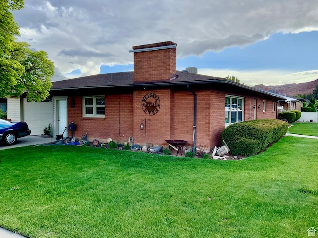 111 W 570 N, Richfield, UT 84701 - view of home's exterior featuring an attached garage, a chimney, a lawn, brick siding, and a mountain view