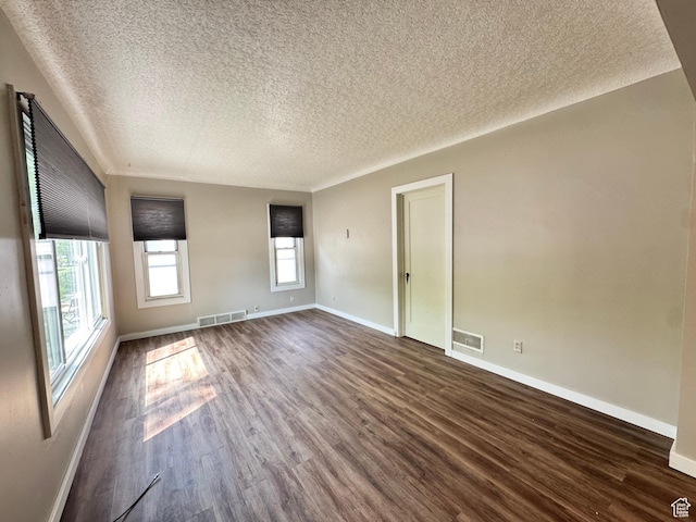 unfurnished living room featuring a textured ceiling, dark wood-type flooring, and baseboards