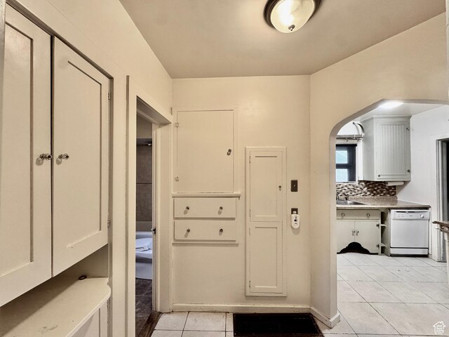 mudroom featuring light tile patterned floors, arched walkways, and a sink