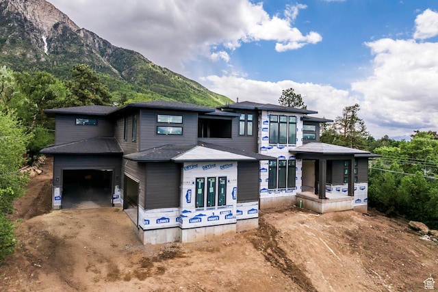 view of front of home featuring dirt driveway, a mountain view, and a garage