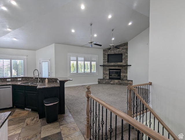 kitchen featuring a sink, stainless steel dishwasher, lofted ceiling, a fireplace, and ceiling fan