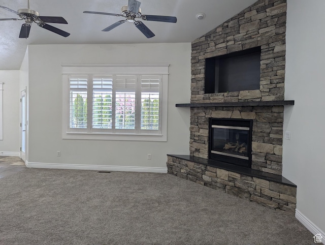 unfurnished living room with ceiling fan, carpet floors, vaulted ceiling, and a stone fireplace