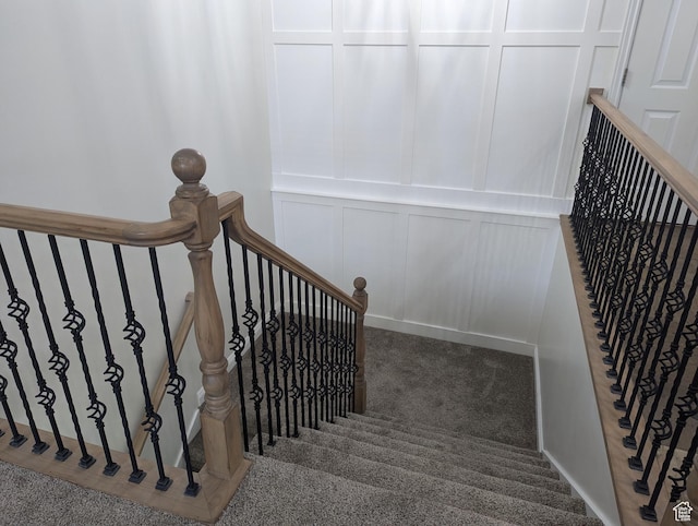 stairs with a decorative wall and carpet floors