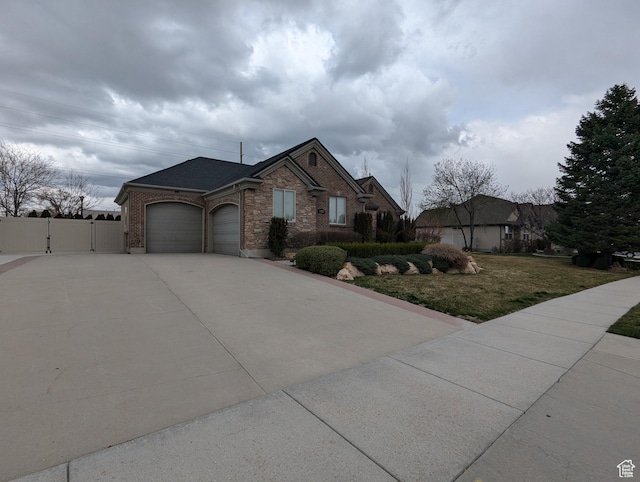 view of front of property with a gate, an attached garage, concrete driveway, and brick siding