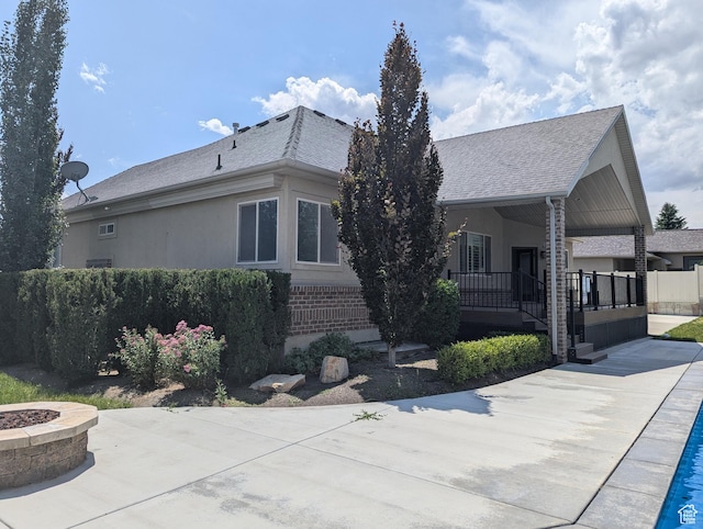 3312 W Country Bluff Rd Unit 5, South Jordan, UT 84095 - view of front facade featuring an outdoor fire pit, a porch, brick siding, roof with shingles, and stucco siding