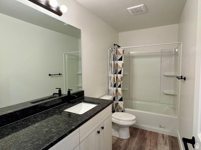 full bath featuring wood finished floors, toilet, a textured ceiling, shower / tub combo, and vanity