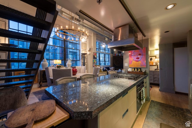 159 W Broadway Unit 411, Salt Lake City, UT 84101 - kitchen with island exhaust hood, stainless steel gas stovetop, a chandelier, wood finished floors, and oven