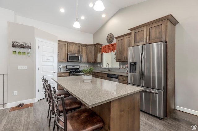 kitchen with stainless steel appliances, a sink, baseboards, a breakfast bar, and recessed lighting