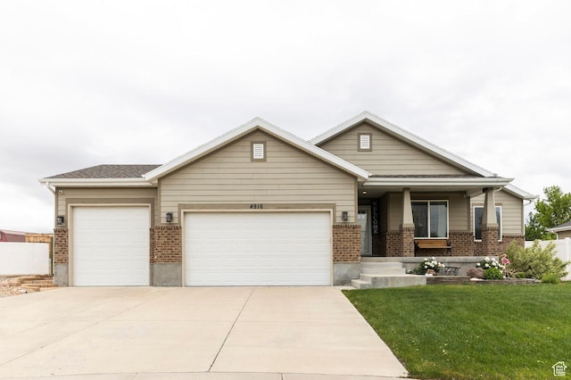 view of front of home with an attached garage, brick siding, a front lawn, driveway, and covered porch