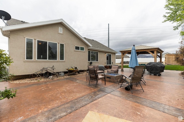 back of house featuring an outdoor fire pit, a gazebo, a patio area, and stucco siding