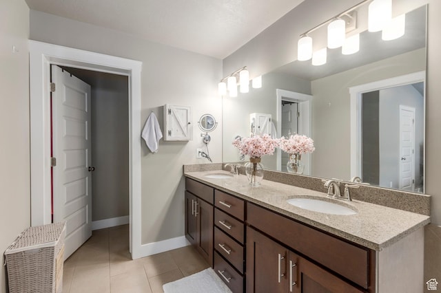 bathroom featuring tile patterned flooring, double vanity, and baseboards