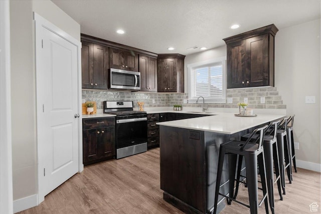 930 N 90 W, Santaquin, UT 84655 - kitchen featuring stainless steel appliances, a sink, baseboards, dark brown cabinets, and a breakfast bar