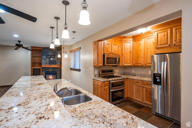 14046 S Emmeline Dr, Herriman, UT 84096 - kitchen with appliances with stainless steel finishes, a sink, a ceiling fan, a tile fireplace, and light stone countertops