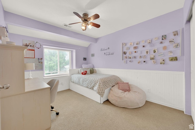 carpeted bedroom featuring a wainscoted wall, ceiling fan, and an office area