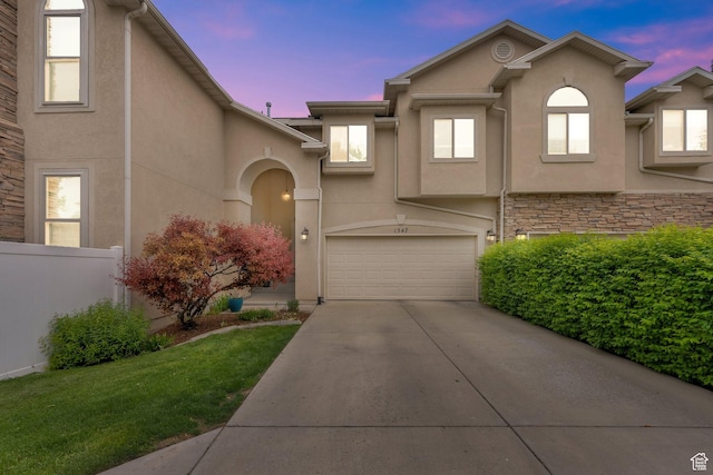 view of front of property featuring stucco siding, concrete driveway, an attached garage, and stone siding