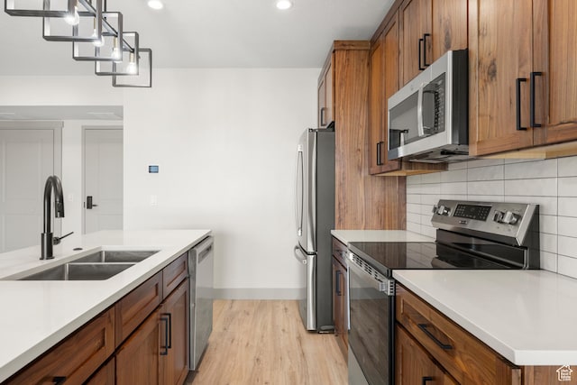 35 E 150th St S Unit D101, Garden City, UT 84028 - kitchen with stainless steel appliances, a sink, light wood-type flooring, brown cabinets, and recessed lighting