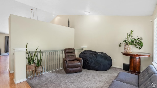 living area featuring lofted ceiling, baseboards, and wood finished floors