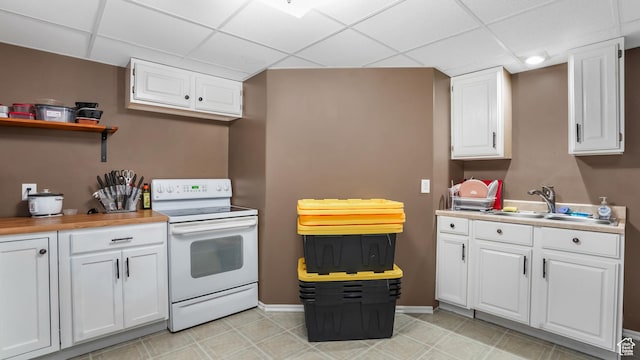 kitchen with electric range, a drop ceiling, a sink, white cabinets, and light countertops