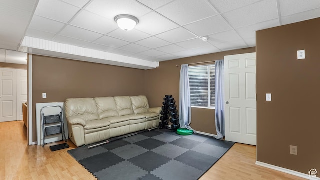 living area with wood finished floors, a drop ceiling, and baseboards