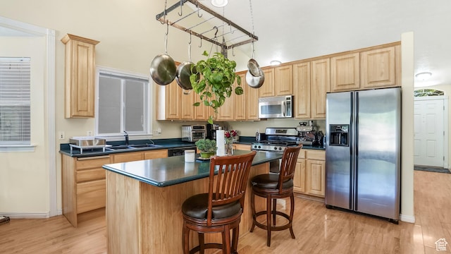 kitchen featuring appliances with stainless steel finishes, a sink, and light brown cabinetry