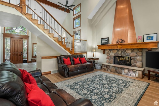 living room featuring a high ceiling, stairs, wood finished floors, a ceiling fan, and a fireplace