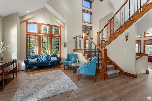 living area with a high ceiling, wood finished floors, baseboards, and stairs
