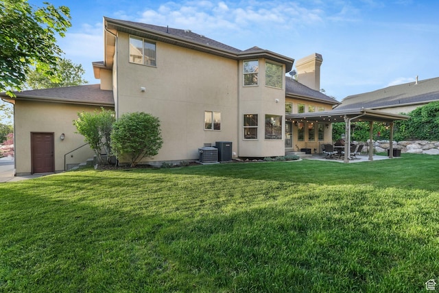rear view of property featuring central AC, a patio area, a yard, a chimney, and stucco siding