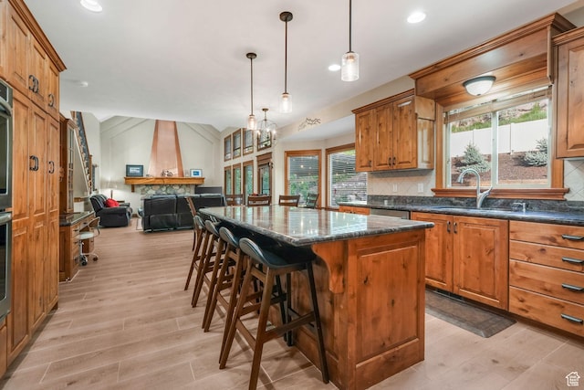 kitchen featuring a sink, a kitchen island, light wood-type flooring, backsplash, and open floor plan