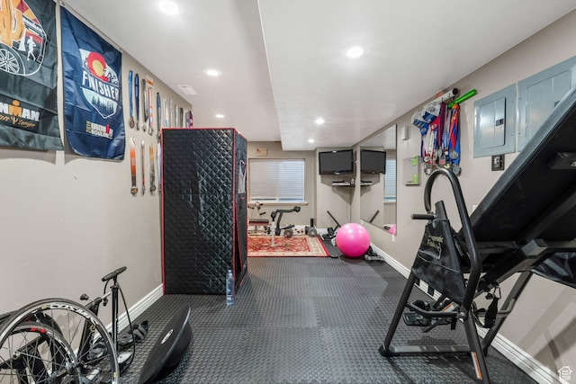 workout area with recessed lighting, baseboards, and electric panel
