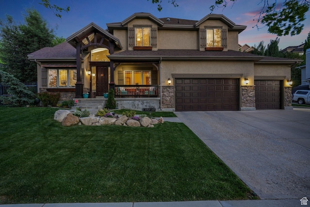 view of front facade with stone siding, a front yard, stucco siding, driveway, and a garage